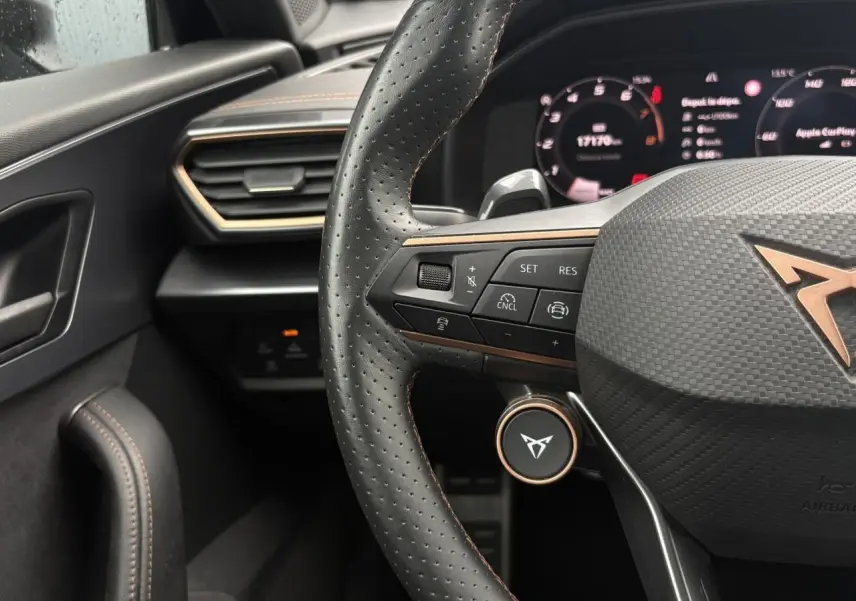 Vue rapprochée du volant cuir perforé noir avec logo CUPRA cuivré et commandes multifonctions du CUPRA Formentor 2025.