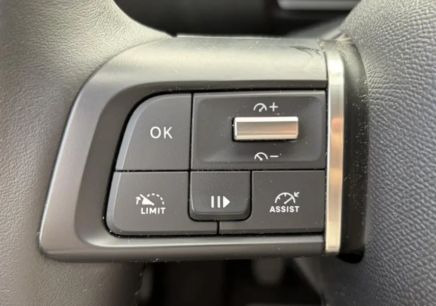 Gros plan sur les commandes de régulateur de vitesse au volant côté gauche d'une Citroën C4 2024 Rouge Elixir.