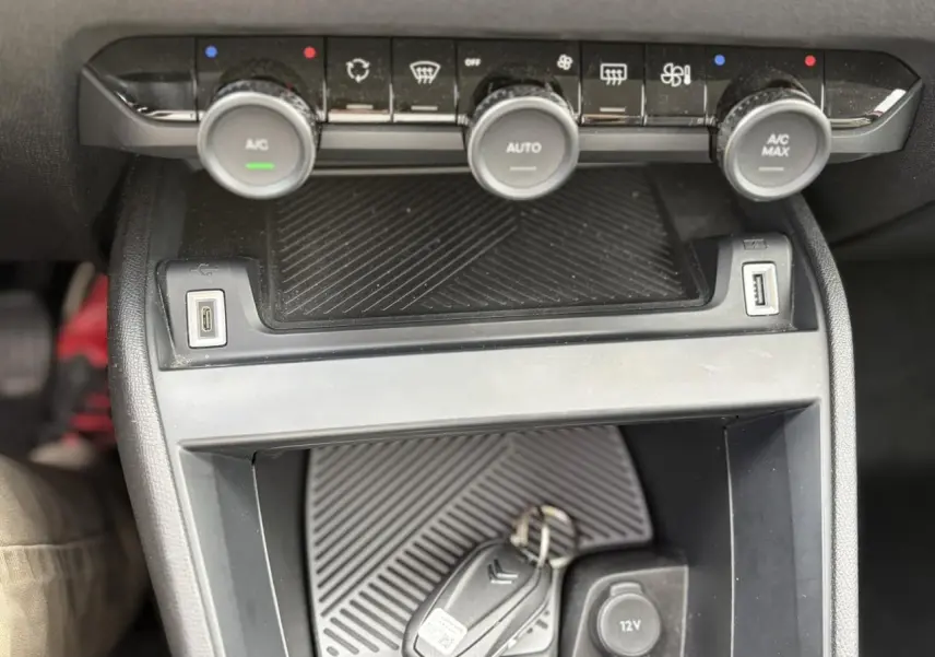 Vue rapprochée de la console centrale noire de la Citroën C4 avec commandes climatisation et clé posée.