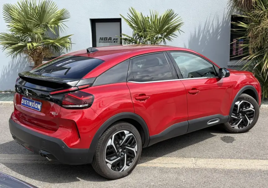 Vue 3/4 arrière droite d'une Citroën C4 2024 Rouge Elixir avec jantes alliage 18'' et toit noir contrasté.