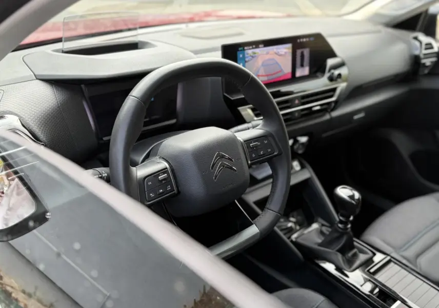 Vue intérieure côté conducteur de la Citroën C4 1.2 PureTech 130 Max avec volant cuir, écran tactile et levier de vitesse manuel.