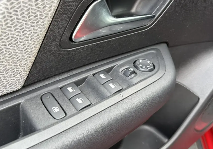 Détail des commandes de lève-vitres et rétroviseurs sur la porte côté conducteur d'une Citroën C4 Rouge Elixir.
