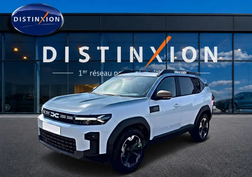 SUV Dacia Bigster blanc vu en 3/4 avant droit, avec jantes noires et barres de toit visibles.