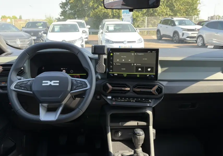 Vue intérieure du tableau de bord du Dacia Bigster blanc 2026, volant multifonction et écran tactile central visible.