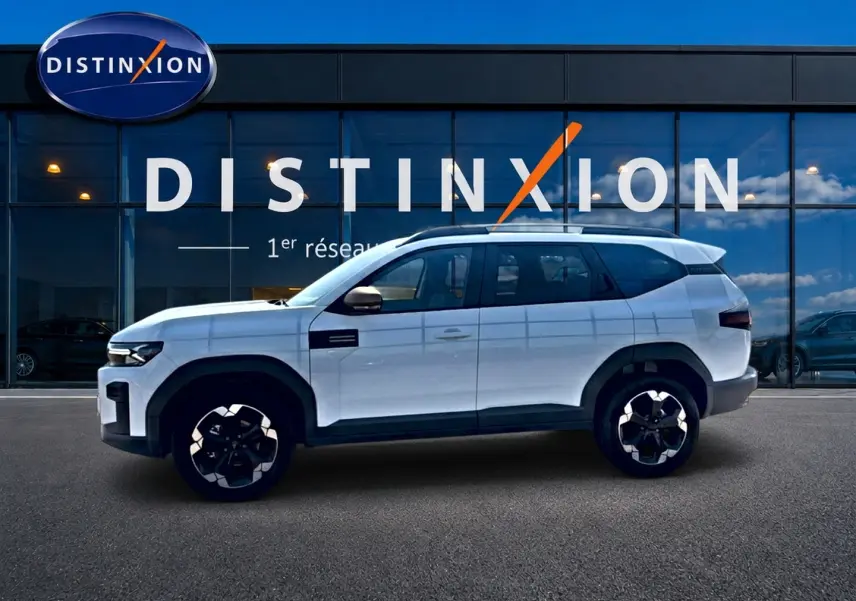 Profil droit du SUV blanc Dacia Bigster 2026 avec jantes noires et détails noirs contrastants, devant une vitrine Distinxion.