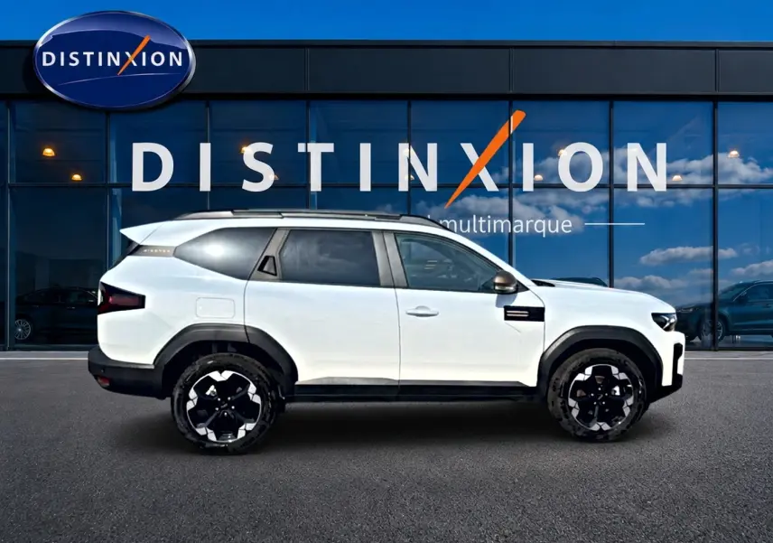 Profil droit du SUV blanc Dacia Bigster 2026 avec jantes noires et détails noirs contrastants, devant une vitrine Distinxion.