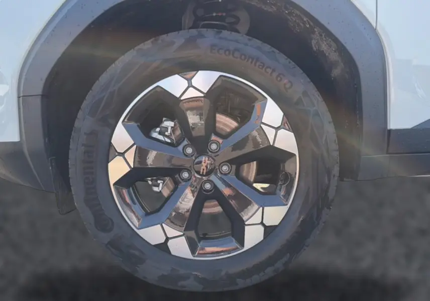 Gros plan sur la roue avant droite du Dacia Bigster blanc, jante alu bicolore au design géométrique.