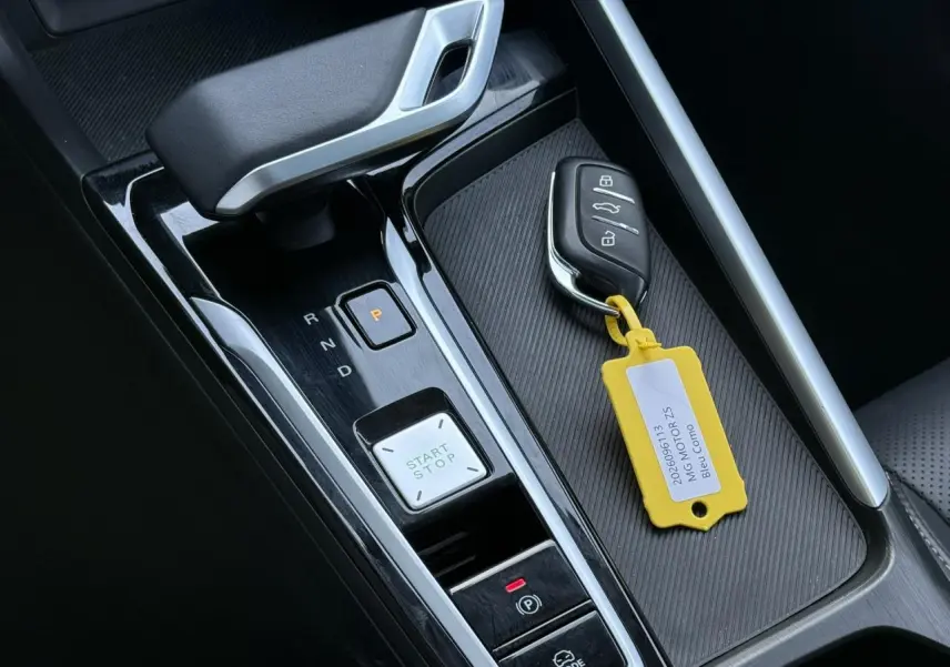 Gros plan sur la console centrale noire du MG ZS Hybrid+ 2025 avec levier de vitesse automatique et clé avec étiquette jaune.