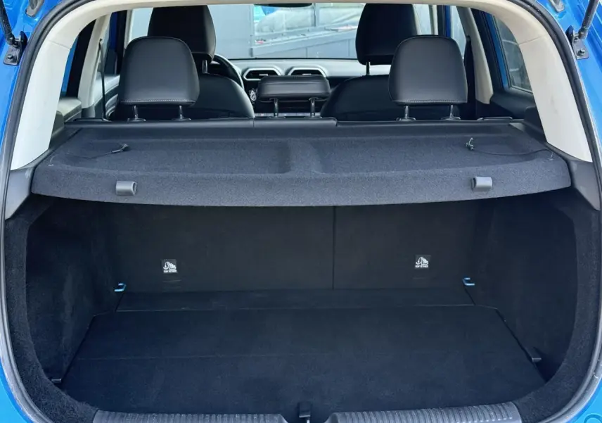 Coffre ouvert d’un MG Motor ZS 1.5 Hybrid+ 197 Luxury bleu Como, avec cache-bagages et sièges arrière noirs visibles.
