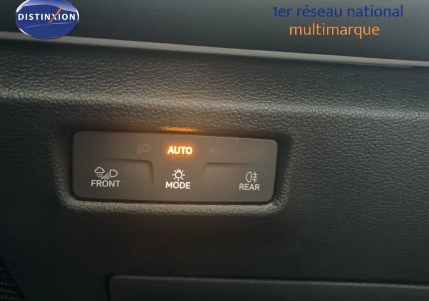 Détail du tableau de bord du Volkswagen Tiguan 2026, montrant les commandes d'éclairage en mode automatique avec rétroéclairage orange.