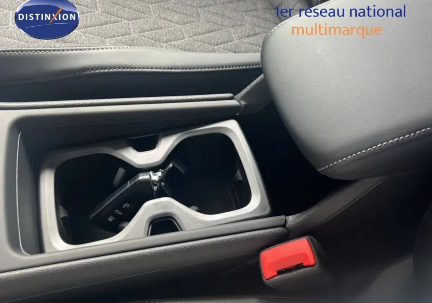 Gros plan intérieur sur le porte-gobelets central avec clé Volkswagen, sellerie cuir noir et accoudoir visible.