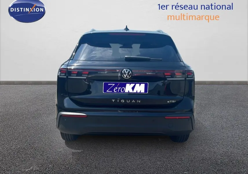 Vue arrière d'un Volkswagen Tiguan noir grenadilla métal, mettant en valeur ses feux arrière étirés et son design épuré.