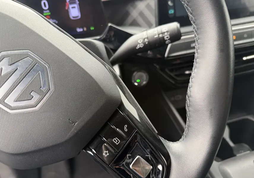 Gros plan sur le volant noir du MG3 1.5 HYBRID+ 195 LUXURY avec commandes intégrées et tableau de bord partiel en arrière-plan.