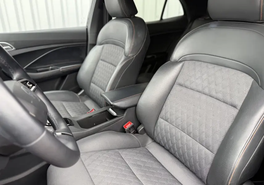 Vue intérieure rapprochée des sièges avant en cuir noir avec surpiqûres orange du MG3 1.5 HYBRID+ 195 LUXURY 2025.