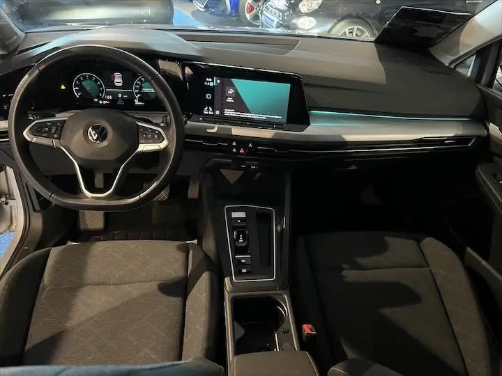Intérieur de Volkswagen Golf 8 essence, vue de face sur tableau de bord et volant, finition noire moderne avec écran tactile.