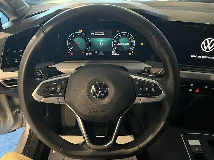Vue rapprochée du volant multifonction et du tableau de bord numérique d'une Volkswagen Golf 8 essence couleur reflet d'argent.