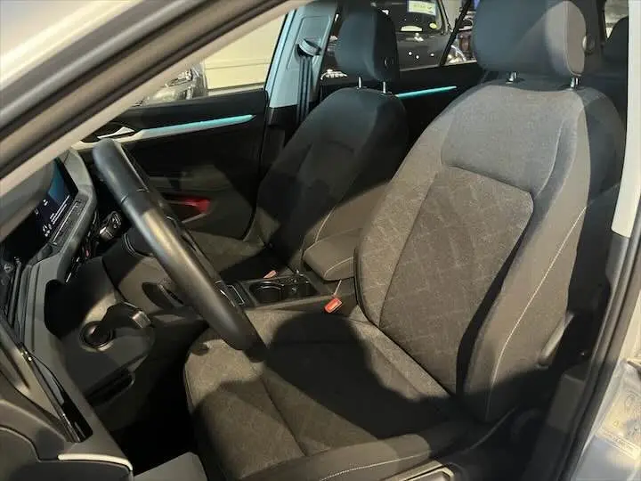 Intérieur avant droit de Volkswagen Golf 8 essence 2021, sièges tissu noir et tableau de bord moderne.