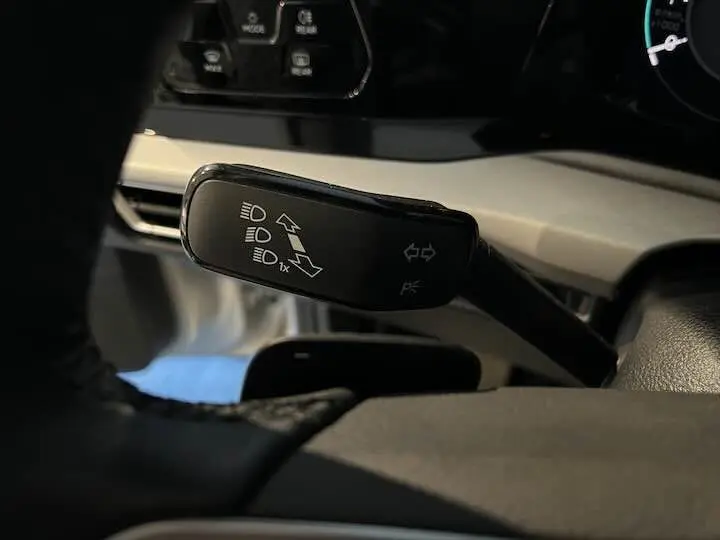 Gros plan sur la manette de clignotant noire du Volkswagen Golf 8, côté gauche du volant, intérieur sombre.