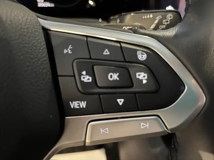 Gros plan sur les commandes multifonctions noires et argentées du volant d'une Volkswagen Golf 8 Essence 2021.