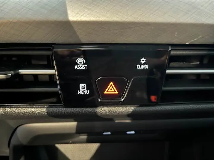 Panneau central du tableau de bord de la Volkswagen Golf 8 argent, avec boutons d'alerte et climatisation visibles.