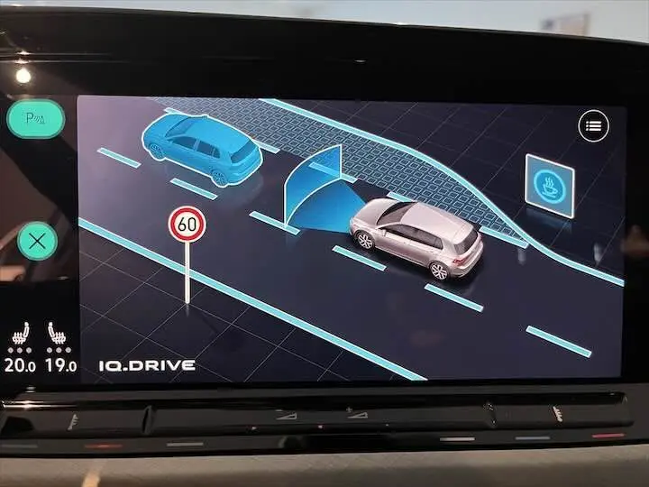 Affichage numérique intérieur montrant la Volkswagen Golf 8 argent en assistance au stationnement avec capteurs et limite de vitesse à 60 km/h