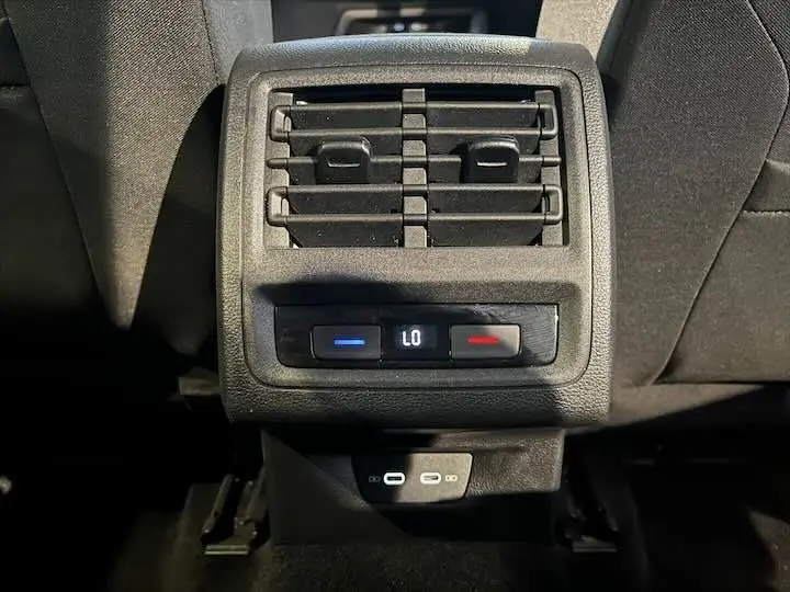 Gros plan sur la ventilation arrière et commandes de climatisation d'une Volkswagen Golf 8 essence, intérieur noir.