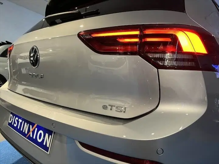 Vue arrière droite d'une Volkswagen Golf 8 1.0 E TSI argent métal avec feux arrière allumés et logo distinctif gTSI.