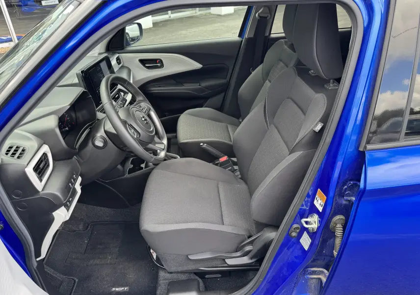 Vue intérieure côté conducteur de la Suzuki Swift 1.2 Hybrid Privilege bleu, montrant les sièges et le tableau de bord moderne.