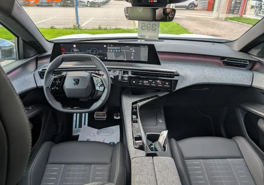 Vue intérieure avant du Peugeot 3008 blanc 2025 GT, avec tableau de bord numérique et sellerie tissu gris et noir.