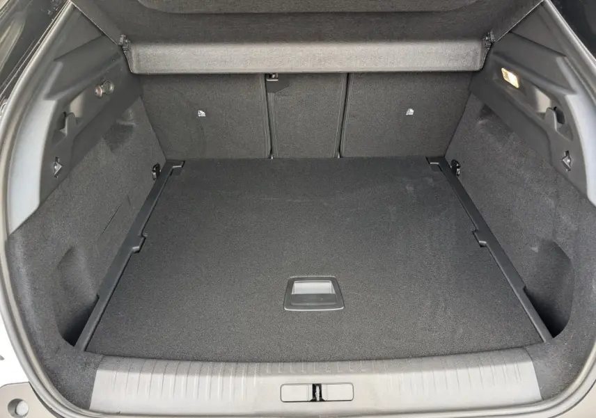 Coffre spacieux du Peugeot 3008 blanc 2025, vue arrière ouverte, moquette noire et éclairage intérieur visible.