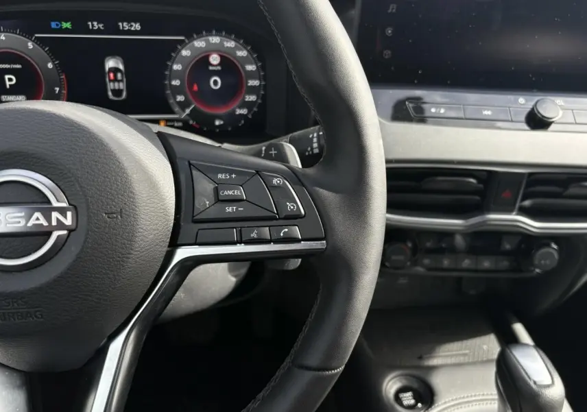 Vue rapprochée du volant noir et du tableau de bord numérique du Nissan Juke 2025 gris Ceramic.