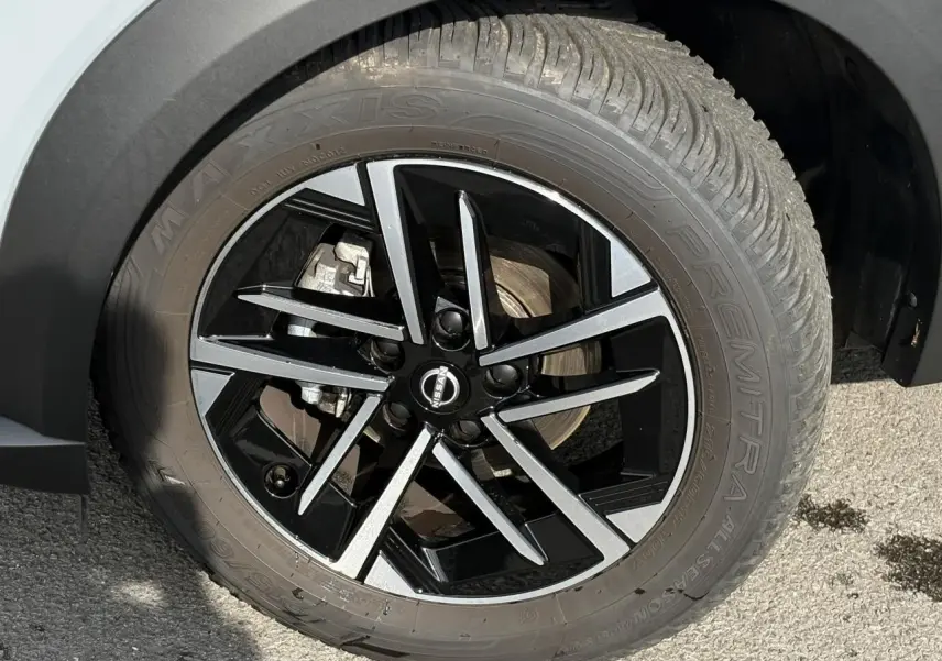 Gros plan sur la roue avant droite du Nissan Juke 2025 gris Ceramic avec jante alliage noire et argentée.