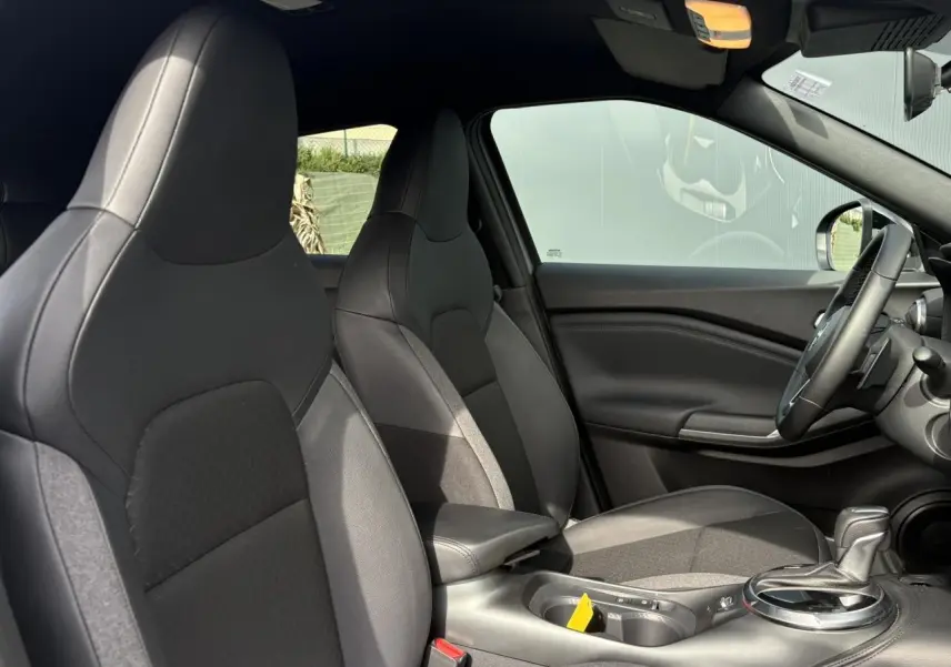 Vue intérieure côté droit du Nissan Juke 2025 gris Ceramic, montrant les sièges avant et la console centrale avec levier de vitesse.