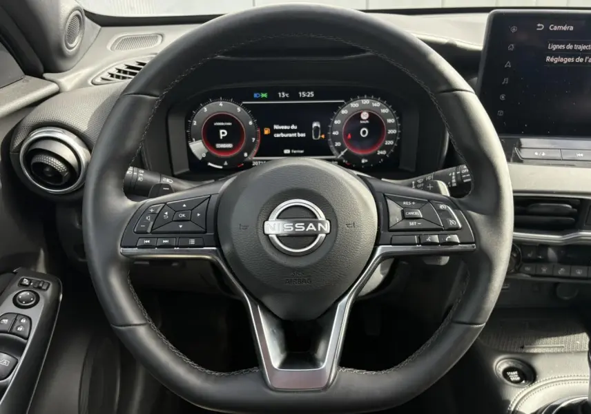 Vue intérieure centrée sur le volant noir du Nissan Juke 2025 avec tableau de bord digital et écran tactile.