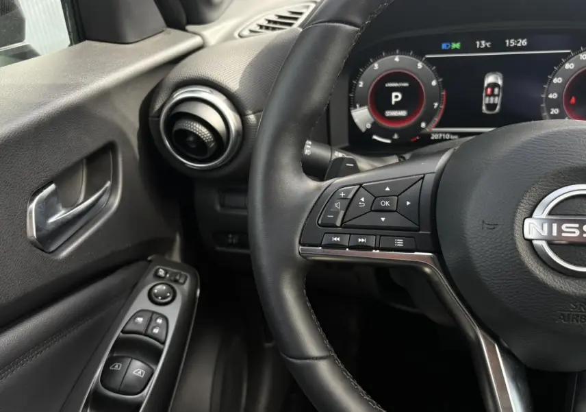 Vue intérieure côté conducteur du tableau de bord et volant noir du Nissan Juke 2025 avec commandes au volant visibles.