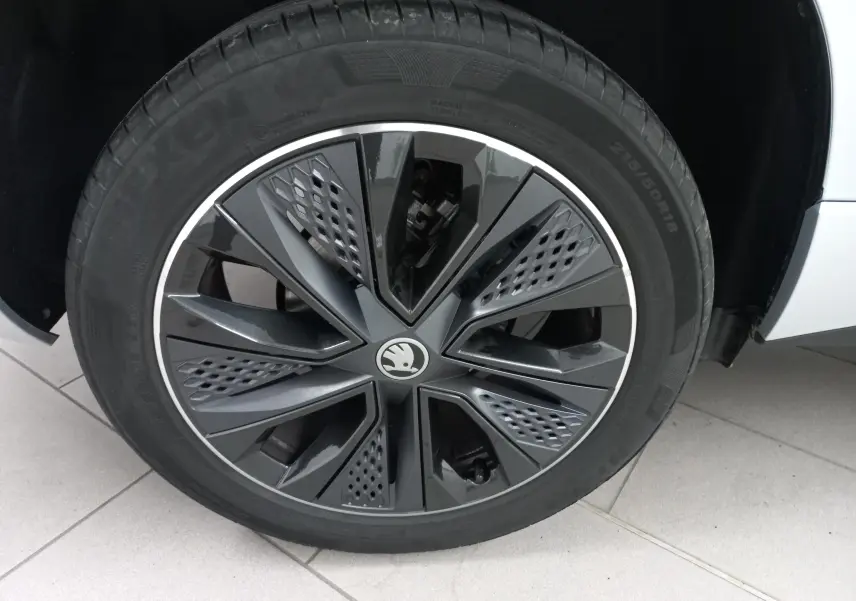 Gros plan sur la roue avant droite du Skoda Karoq gris argent, mettant en valeur la jante noire au design moderne.