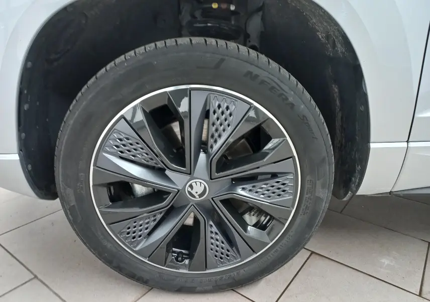 Gros plan sur la roue avant gauche du Skoda Karoq gris argent, mettant en valeur la jante au design moderne et sportif.