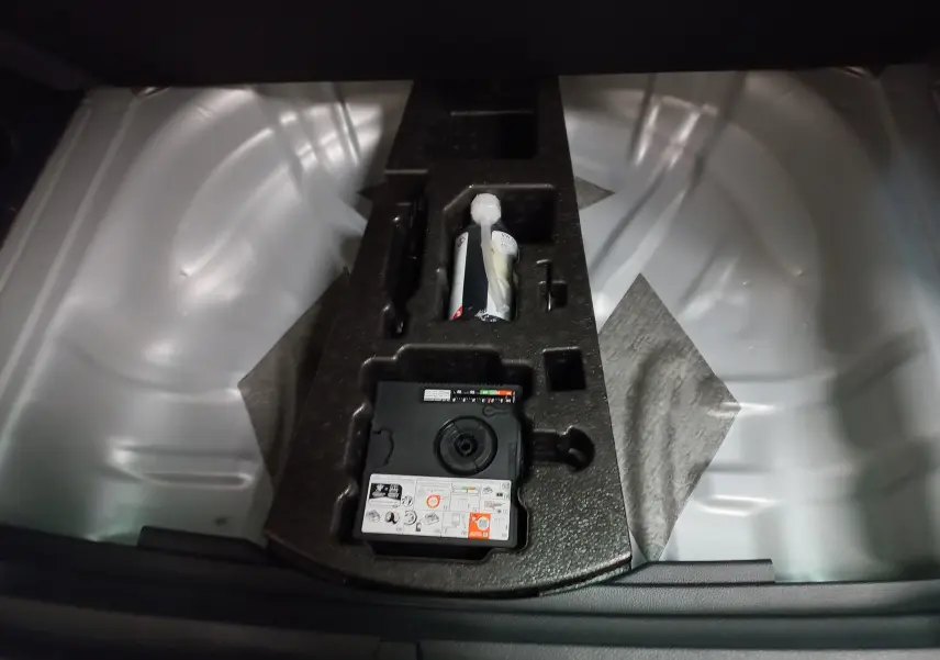 Gros plan sur le coffre du Skoda Karoq 2025 gris argent, montrant le plancher de chargement variable et le kit de réparation.