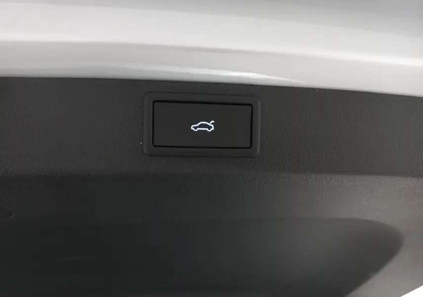 Bouton d'ouverture électrique du hayon sur le bord intérieur du coffre d'un Skoda Karoq gris argent 2025.