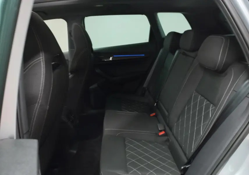 Vue intérieure côté gauche des sièges arrière noirs avec surpiqûres blanches du Skoda Karoq gris argent 2025.