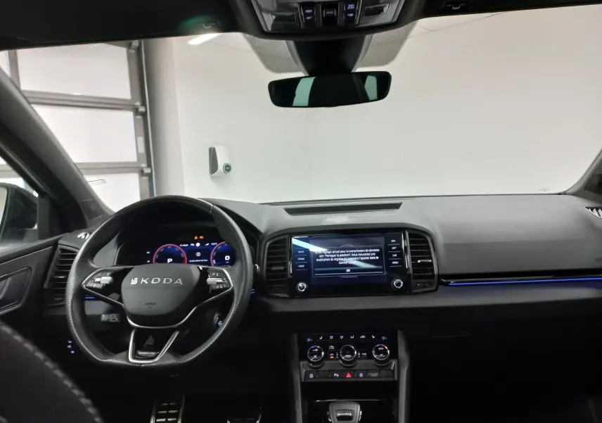 Vue intérieure avant du Skoda Karoq gris argent 2025, avec tableau de bord numérique et écran tactile central allumé.