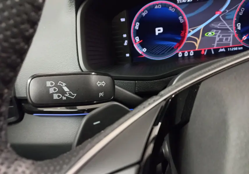 Détail du combiné d'instruments et commande de feux sur le volant d'un Skoda Karoq 2025, intérieur noir.