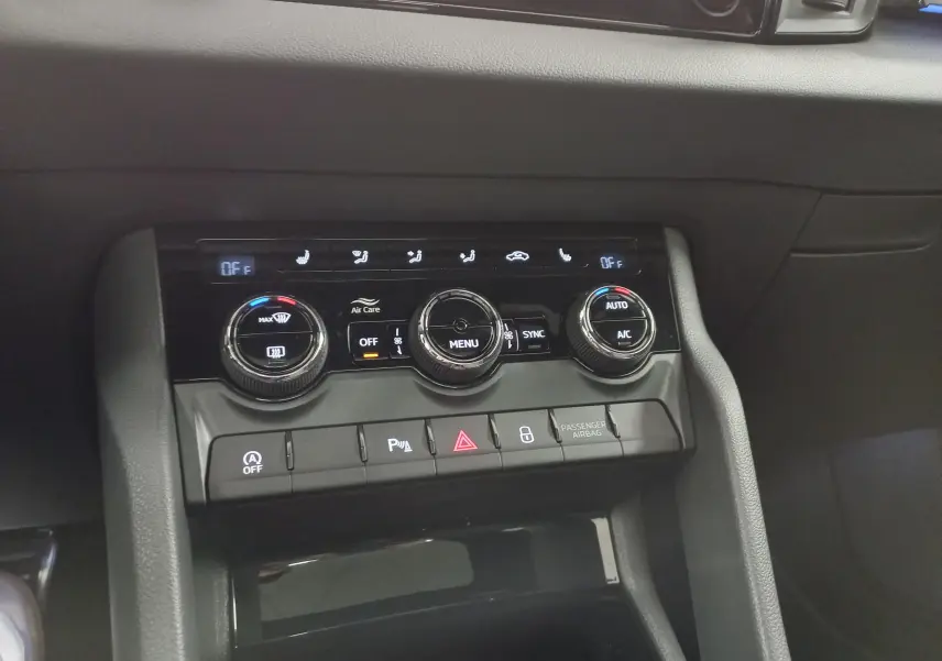 Gros plan sur la console centrale du Skoda Karoq 2025, avec commandes climatisation et boutons fonctionnels en noir mat.