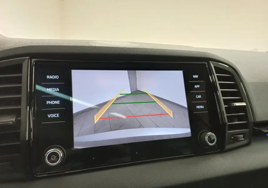 Écran central du Skoda Karoq 2025 affichant la caméra de recul avec lignes de guidage colorées, intérieur noir.