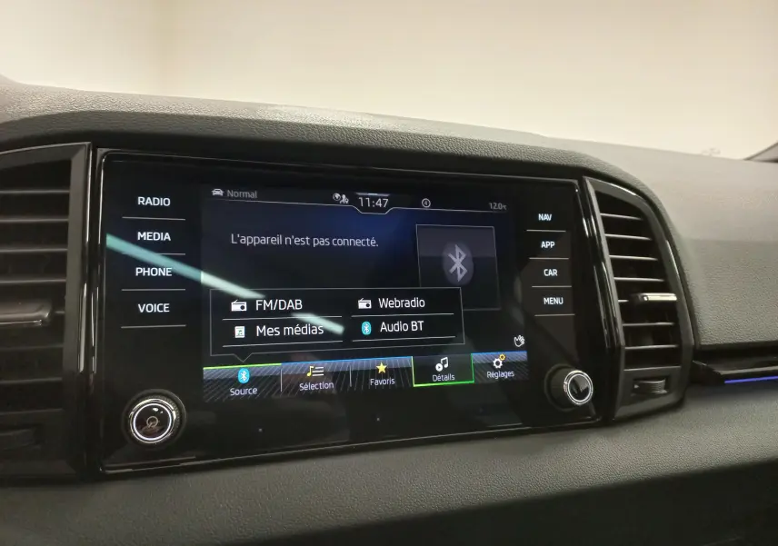 Écran tactile central du tableau de bord du Skoda Karoq gris argent, affichant les options multimédias et Bluetooth.