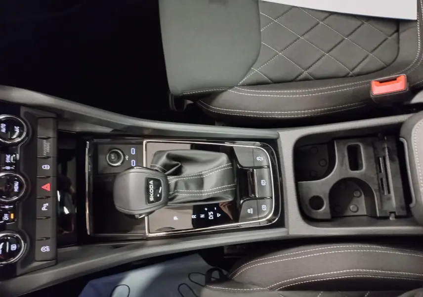 Vue plongeante sur la console centrale du Skoda Karoq 2025, avec levier de vitesse DSG7 et sellerie noire matelassée.