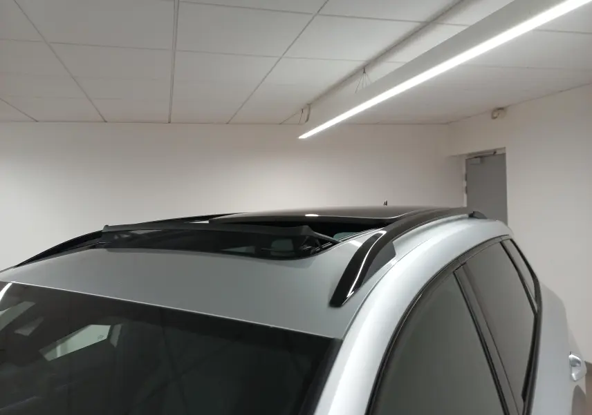 Vue rapprochée du toit ouvrant panoramique en verre du Skoda Karoq gris argent, avec barres de toit noires visibles.
