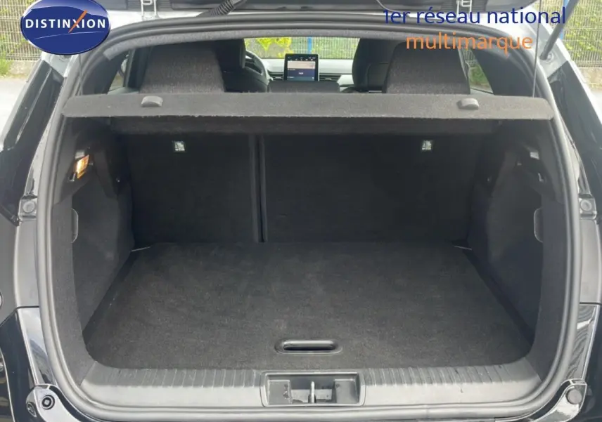 Coffre ouvert vu de l'arrière d'un Renault Captur noir étoile métal avec intérieur sombre et tablette arrière visible.