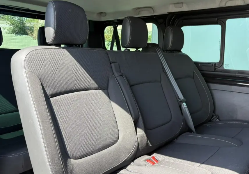 Vue intérieure sur la deuxième rangée de sièges noirs du Nissan Primastar Combi 2025, avec ceintures et appuie-têtes visibles.