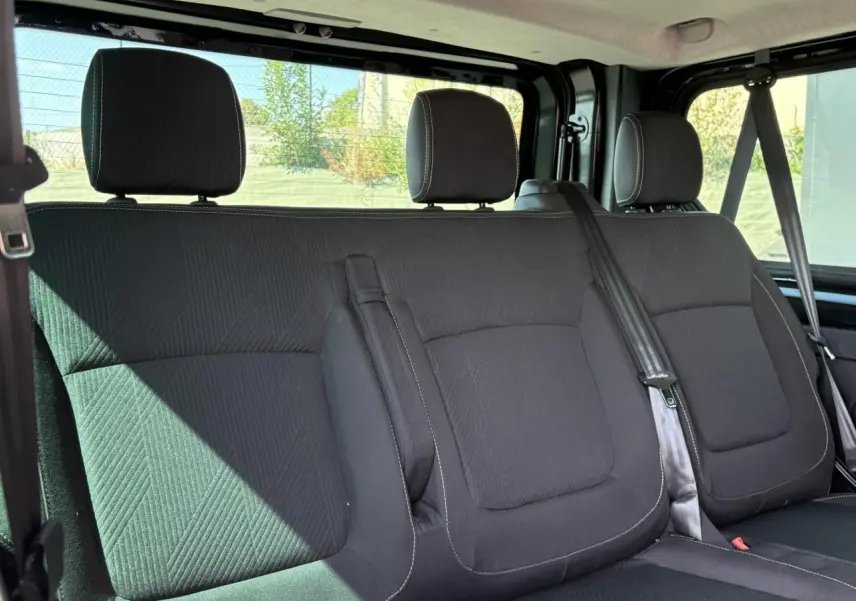 Vue intérieure sur la banquette arrière noire du Nissan Primastar Combi 2025 avec ceintures de sécurité visibles.